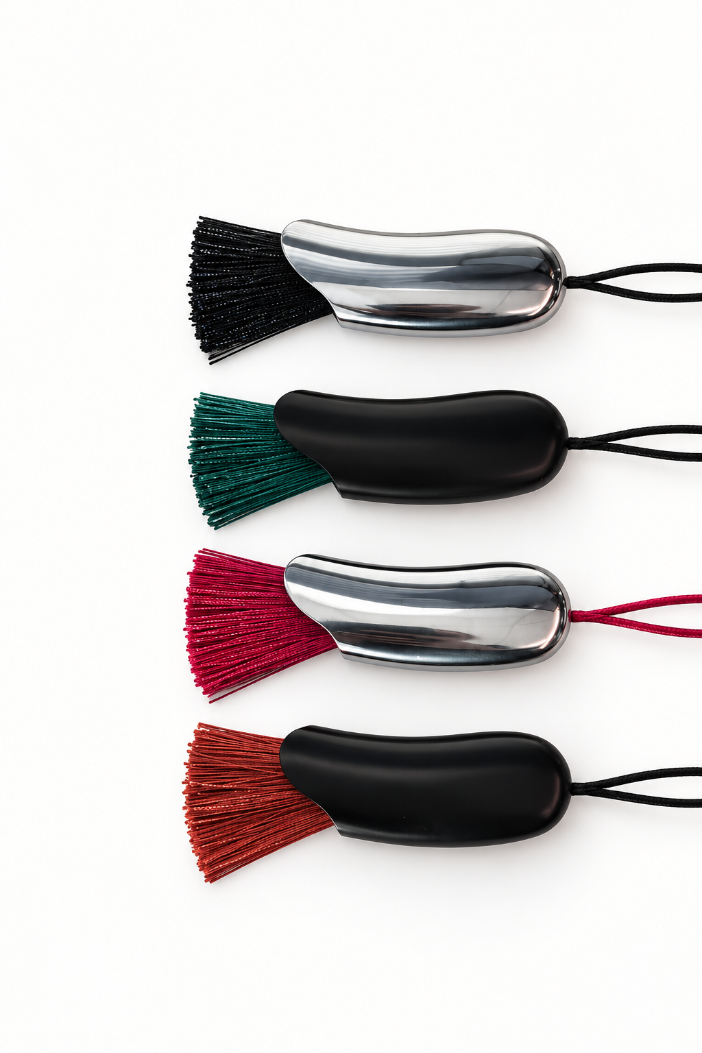 Four shiny black necklaces arranged vertically on a white background, each with a cord, shiny metallic cap, and different colored bristles in black, green, red, and rust.