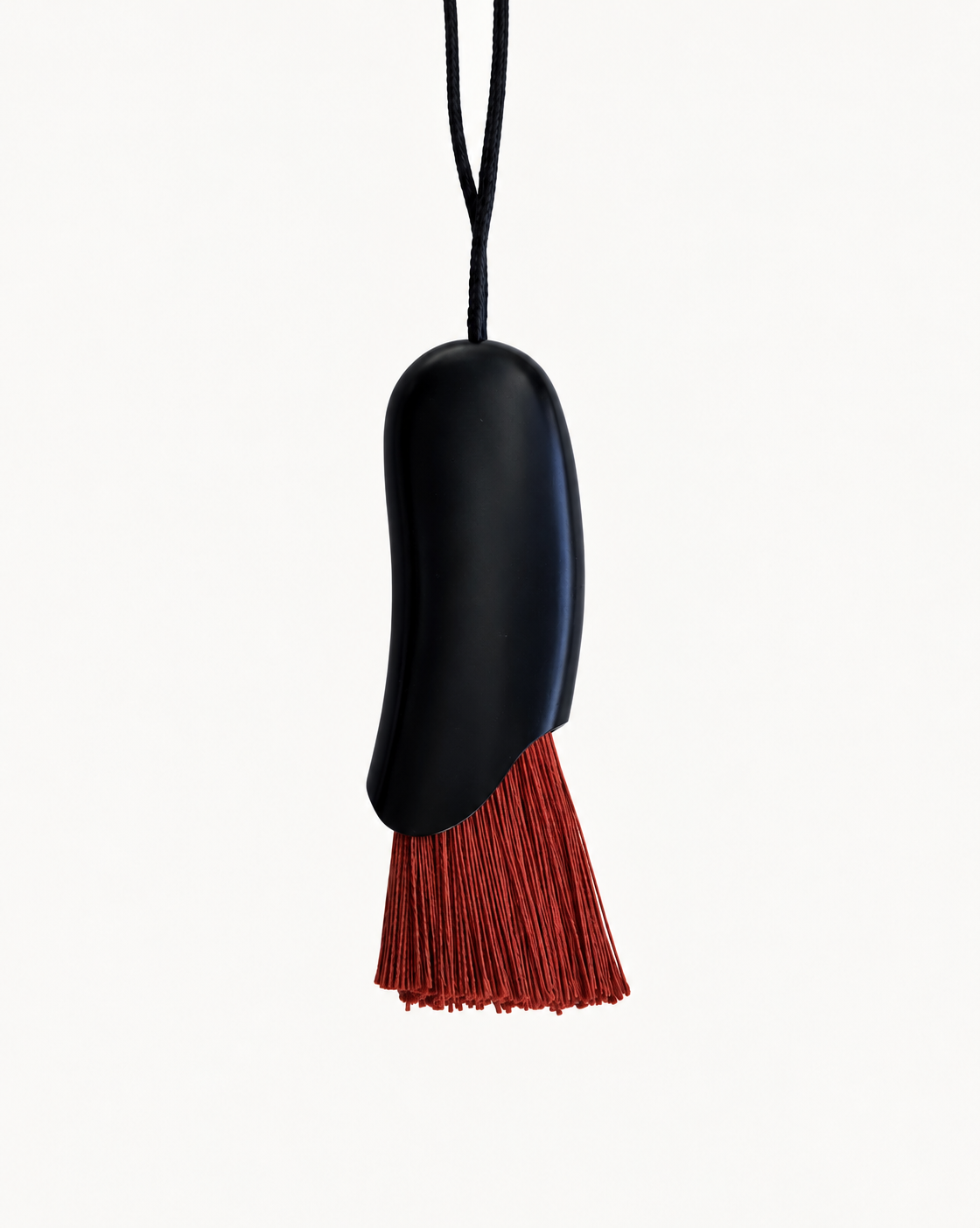 A minimalist black pendant with a textured brown tassel-like bottom and a black cord, photographed against a clean white background.