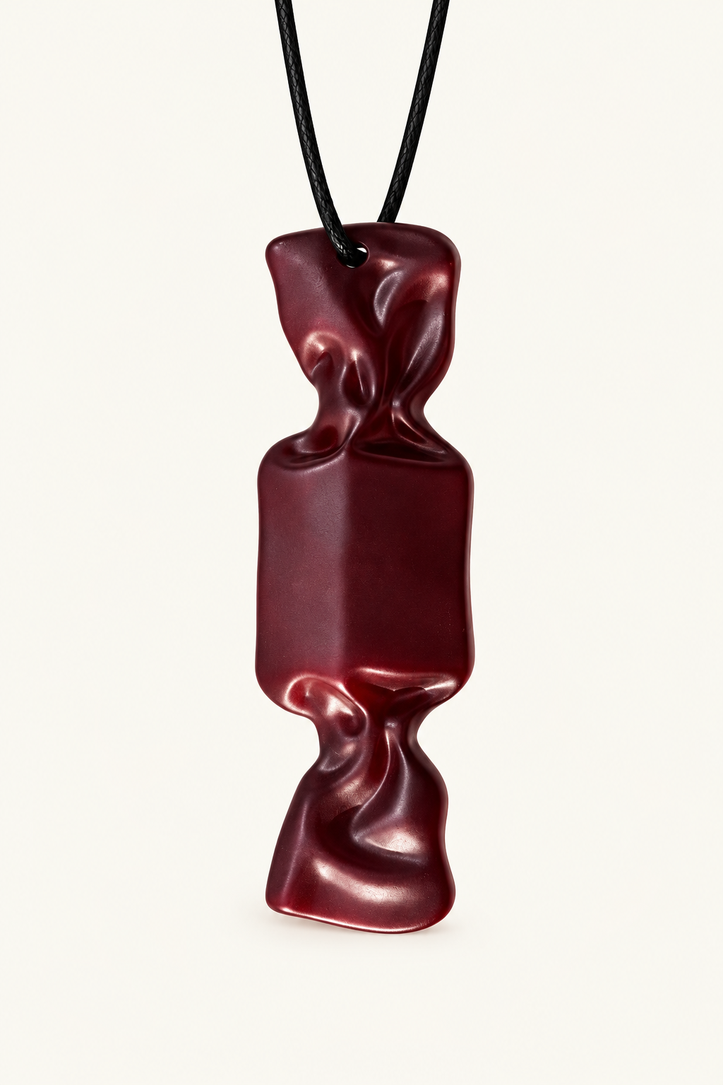A dark red, sculptural candy pendant, suspended from a simple black cord against a clean, off-white background.
