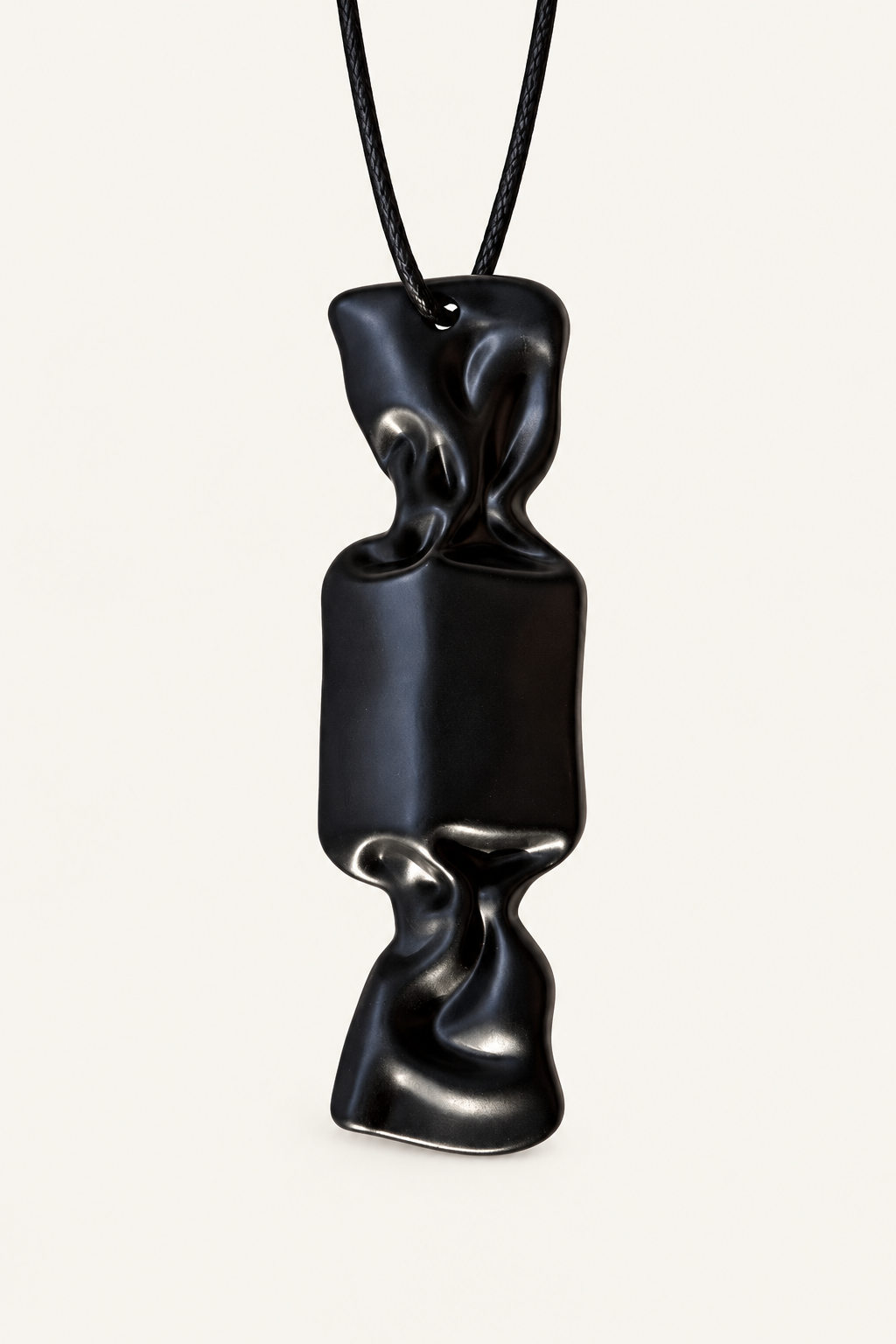 A black sculptural candy pendant necklace with an organic, fluid silhouette, suspended from a black cord against a light off-white background.
